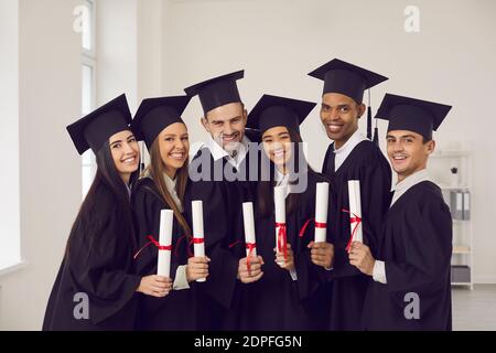 Portrait d'un groupe de diplômés universitaires multiraciaux heureux avec des diplômes entre leurs mains. Banque D'Images