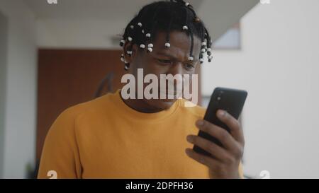 Portrait d'un homme noir afro-américain heureux surpris lisant un message texte sur son smartphone. Photo de haute qualité Banque D'Images