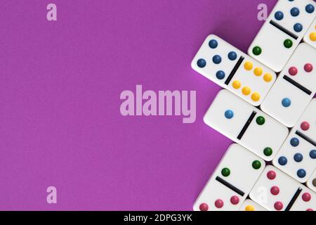 Dominos colorés disposés sur fond violet avec un espace négatif pour copier Banque D'Images