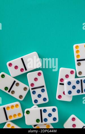 Dominos colorés disposés sur fond bleu aqua avec espace négatif pour copie Banque D'Images