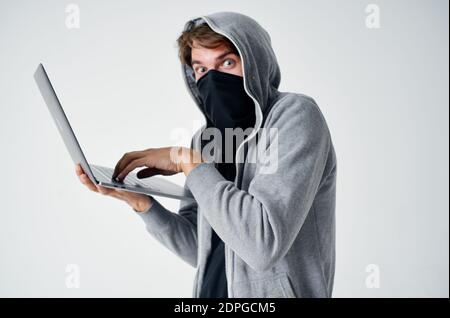 homme dans le noir gris avec ordinateur portable masque caché piratage ordinateur Banque D'Images