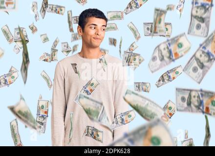 Jeune homme amérindien africain portant des vêtements décontractés souriant à côté et regardant loin de penser. Banque D'Images