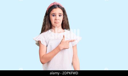 Adorable enfant hispanique fille portant une chemise blanche décontractée pointant de côté inquiet et nerveux avec index, inquiet et expression surprise Banque D'Images