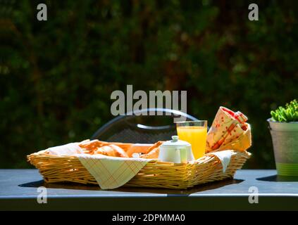 Vue sur la façade du petit déjeuner frais servi le matin sur une assiette en osier plateau de table de café en plein air avec espace de copie de bokeh vert arrière-plan Banque D'Images