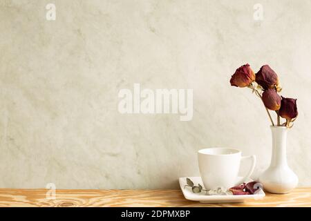 Tasse de café avec vase de rose rouge sec sur table en bois. Intérieur de la maison Banque D'Images