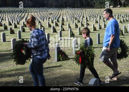 Bushnell, États-Unis. 19 décembre 2020. La famille DeGeorge de Tampa, en Floride, porte des couronnes à placer aux pierres angulaires des anciens combattants militaires américains au cimetière national de Floride.aujourd'hui, les bénévoles ont déposé 1.7 millions de couronnes dans 2,557 endroits participants aux États-Unis pour se souvenir et honorer les anciens combattants américains morts. Crédit : SOPA Images Limited/Alamy Live News Banque D'Images