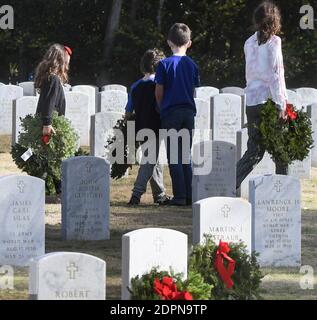 Bushnell, États-Unis. 19 décembre 2020. La famille Bauman de St. Johns, en Floride, porte des couronnes à placer aux pierres angulaires des anciens combattants militaires américains au cimetière national de Floride.aujourd'hui, les bénévoles ont déposé 1.7 millions de couronnes dans 2,557 endroits participants aux États-Unis pour se souvenir et honorer les anciens combattants américains tombés. Crédit : SOPA Images Limited/Alamy Live News Banque D'Images