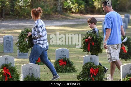 Bushnell, États-Unis. 19 décembre 2020. La famille DeGeorge de Tampa, en Floride, porte des couronnes à placer aux pierres angulaires des anciens combattants militaires américains au cimetière national de Floride.aujourd'hui, les bénévoles ont déposé 1.7 millions de couronnes dans 2,557 endroits participants aux États-Unis pour se souvenir et honorer les anciens combattants américains morts. Crédit : SOPA Images Limited/Alamy Live News Banque D'Images