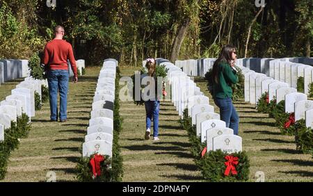 Bushnell, États-Unis. 19 décembre 2020. Une famille porte des couronnes à déposer sur les pierres tombales des anciens combattants américains au cimetière national de Floride.aujourd'hui, les bénévoles ont déposé 1.7 millions de couronnes dans 2,557 endroits participants aux États-Unis pour se souvenir et honorer les anciens combattants américains morts. Crédit : SOPA Images Limited/Alamy Live News Banque D'Images