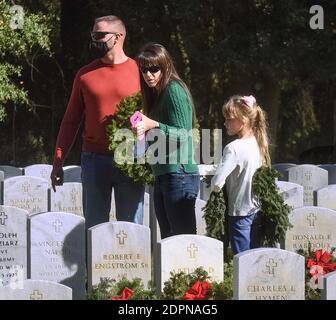 Bushnell, États-Unis. 19 décembre 2020. Une famille porte des couronnes à déposer sur les pierres tombales des anciens combattants américains au cimetière national de Floride.aujourd'hui, les bénévoles ont déposé 1.7 millions de couronnes dans 2,557 endroits participants aux États-Unis pour se souvenir et honorer les anciens combattants américains morts. Crédit : SOPA Images Limited/Alamy Live News Banque D'Images