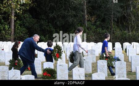 Bushnell, États-Unis. 19 décembre 2020. La famille Bauman de St. Johns, en Floride, porte des couronnes à placer aux pierres angulaires des anciens combattants militaires américains au cimetière national de Floride.aujourd'hui, les bénévoles ont déposé 1.7 millions de couronnes dans 2,557 endroits participants aux États-Unis pour se souvenir et honorer les anciens combattants américains tombés. Crédit : SOPA Images Limited/Alamy Live News Banque D'Images