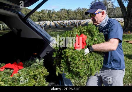 Bushnell, États-Unis. 19 décembre 2020. Un volontaire dépose des couronnes dans une voiture pour que les gens puissent les placer aux pierres angulaires des anciens combattants de l'armée américaine au cimetière national de Floride.aujourd'hui, les bénévoles ont déposé 1.7 millions de couronnes dans 2,557 endroits participants aux États-Unis afin de se souvenir et d'honorer les anciens combattants américains tombés. Crédit : SOPA Images Limited/Alamy Live News Banque D'Images