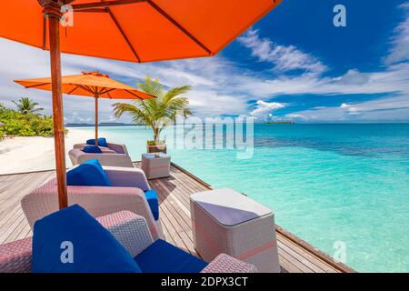 Chaises longues en bois sous parasols avec vue sur l'océan sur l'île tropicale. Resort de luxe été, détente au frais vibes, vacances paysage de voyage Banque D'Images