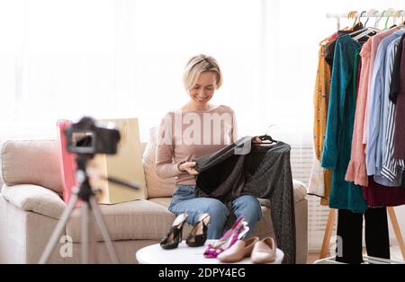 Blog beauté et mode. Jeune femme vlogger enregistrement vidéo sur la nouvelle collection de vêtements, montrant la robe à l'appareil-photo Banque D'Images