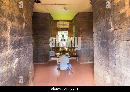 Un bouddhiste thaïlandais prie un des autels à l'intérieur de Wat Kamphaeng Laeng à Phetchaburi, en Thaïlande Banque D'Images