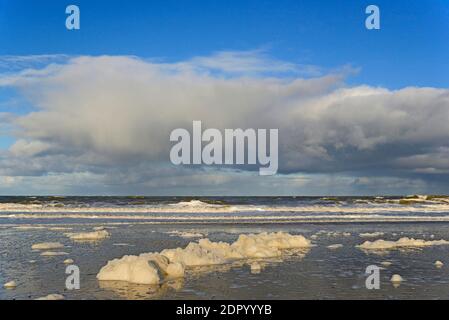 Vagues sur une plage de sable avec formation de mousse, ciel bleu avec des nuages profonds d'enflure (cumulus) au-dessus de la mer du Nord, Norderney, îles de la Frise orientale, Lower Banque D'Images