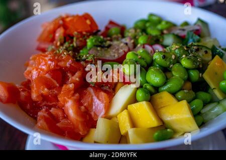 Saumon poke avec avocat et mangue, algues, carottes marinées, concombre. Gros plan Banque D'Images