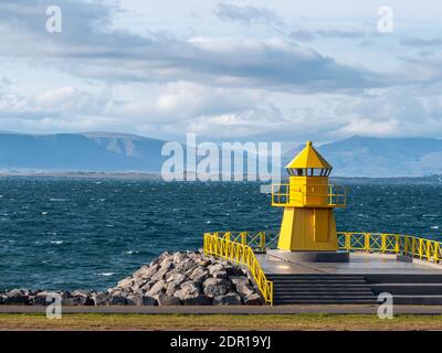 La tour phare jaune sur les brise-lames en pierre, l'entrée au port de Reykjavik Banque D'Images