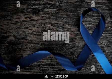 Vue de dessus du ruban bleu foncé sur fond en bois avec espace de copie. Côlon, estomac, cancer colorectal, sensibilisation à l'arthrite et prévention de la violence envers les enfants. Banque D'Images