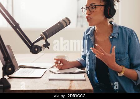 Jeune femme enregistrant et diffusant son podcast depuis sa maison. Femme travaillant à domicile et exécutant son émission de radio. Banque D'Images