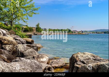 Rive du lac de Neuchâtel. Très beau temps ensoleillé. Nuages rares de beau temps dans le ciel bleu. Un quai coupe le paysage. Au premier plan. Banque D'Images