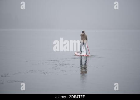 Homme debout sur un paddleboard debout sur un lac glacé Banque D'Images