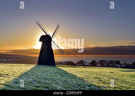 Soleil levant derrière la silhouette du moulin à vent surplombant le canal anglais et le village Rottingdean dans l'est du Sussex, en hiver Banque D'Images