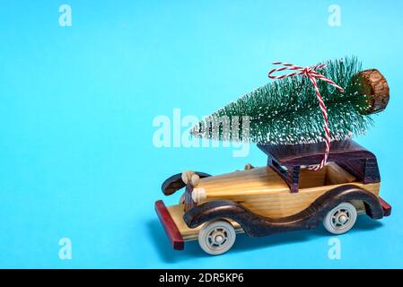 Voiture en bois avec sapin sur le toit sur fond bleu. Concept de célébration de Noël et du nouvel an. Banque D'Images