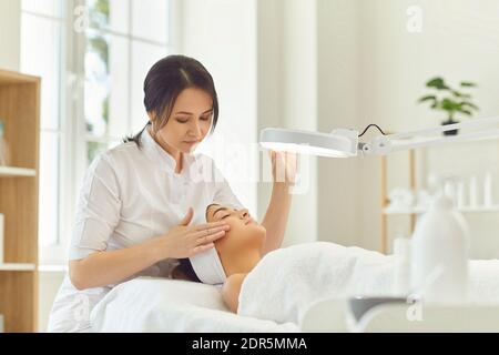Femme dermatologue touchant la joue et vérifiant l'état de la peau du visage de la femme Banque D'Images
