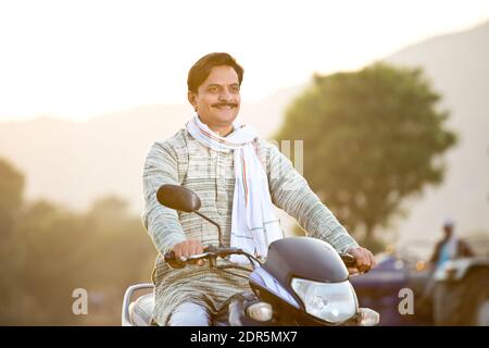 Joyeux Indien rural sur la moto dans le village Banque D'Images