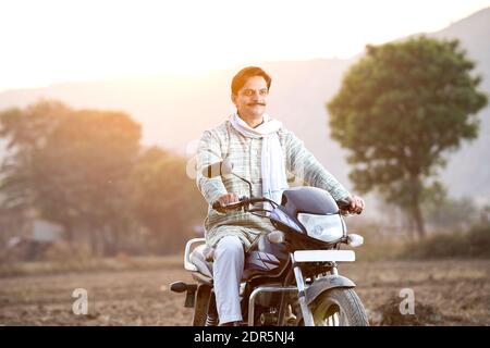 Joyeux Indien rural sur la moto dans le village Banque D'Images