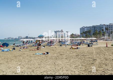 Beaucoup de touristes s'allonger sur des chaises longues sous les parasols À la plage de Larnaca Finikoudes de Chypre en été Banque D'Images