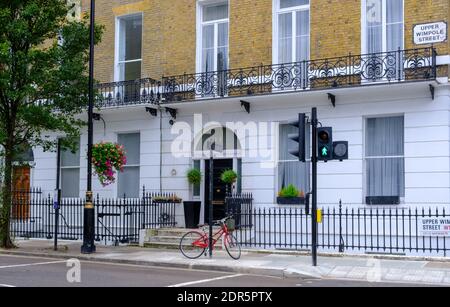 Upper Wimpole Street au coeur de Marylebone Village, Londres, Angleterre. Avec un vélo rouge stationné à l'extérieur. Banque D'Images
