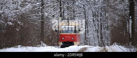 Kiev, Ukraine – 25 décembre 2018 : hiver enneigé. Le vieux tramway rétro rouge roule (va) le long de la route de banlieue. Arrière-plan d'hiver de la forêt de la ville Banque D'Images