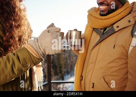 Joyeux jeunes dates interculturelles en hiver en encourageant avec chaud l'hiver, vous vous préparez à un thé dans un ciel dégagé au-dessus des montagnes et de la forêt week-end Banque D'Images