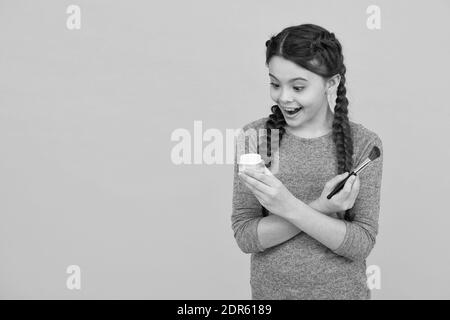 Aimez-vous plus. Concept de soin de la peau. Application de maquillage sur une peau saine. Produits de maquillage pour enfants. Espace de copie. studio de photo de fille faisant le maquillage. Surprise jeune fille faisant le maquillage à l'aide de brosse à poudre. Banque D'Images