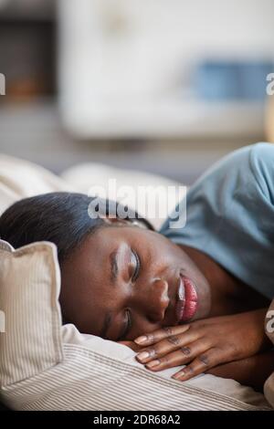 Portrait vertical en gros plan de la jeune femme afro-américaine dormant avec joie draps en coton blanc dans un intérieur confortable Banque D'Images