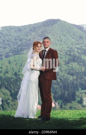 bonne mariée élégante et marié courant et s'amuser dans les montagnes l'été ensoleillé par temps ensoleillé. magnifique couple nouveau-né riant, vrais sentiments. mémoire morte émotionnelle Banque D'Images