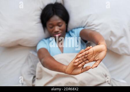 Portrait minimal en haut de la jeune femme afro-américaine qui s'étire avec joie draps en coton blanc pour un lit confortable le matin Banque D'Images