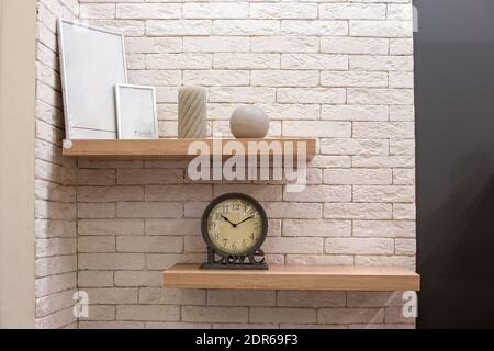 décoration intérieure de la chambre. Étagères en bois avec cadres photo, bougies et une horloge contre un mur de briques légères. Réparations à domicile Banque D'Images