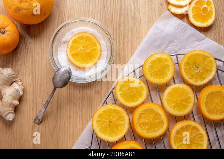 Table en bois avec séchage des tranches d'orange après cuisson au sirop, et un bol avec du sucre et une tranche d'orange. Banque D'Images