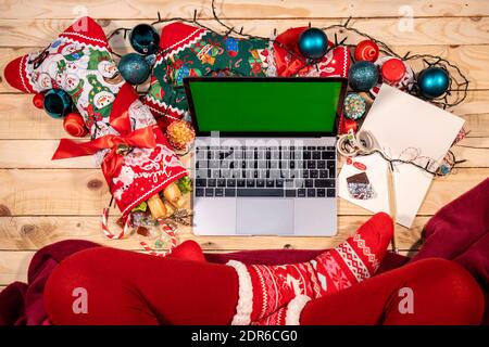 Un coin confortable pour une célébration de Noël à distance en ligne. Des bas remplis de bonbons, une couverture rouge et un ordinateur pour parler avec vos chers. Banque D'Images