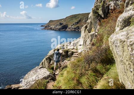 Le randonneur s'attaque à quelques grands pas en pierre sur le sentier de la côte sud-ouest près de la plage de Lamorna Cove, point Penzer, dans les Cornouailles Banque D'Images