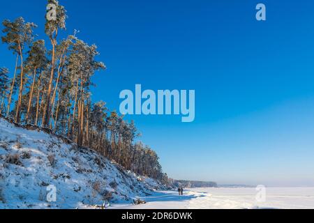 Promenade panoramique dans le froid matin d'hiver. Deux personnes font une promenade sur la côte de la mer gelée. Social distance en hiver. Banque D'Images