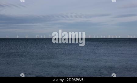 Ferme éolienne à l'horizon en mer avec mer bleu foncé en dessous et ciel bleu pâle au-dessus. Photo de haute qualité avec espace de copie. Banque D'Images