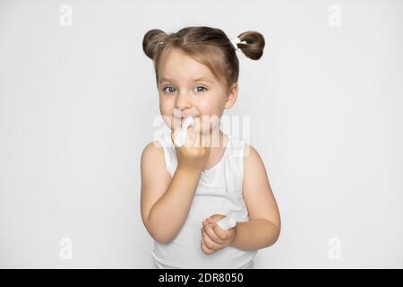 Soins des lèvres, cosmétiques pour enfants. Adorable mignon petite fille de 3 ans appliquant le baume à lèvres sur ses lèvres. Beauté, soin, hydratant et nourrissant avec Banque D'Images