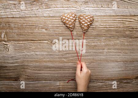 tenir à la main deux pain d'épice sous forme de coeurs fond en bois de fil rouge Banque D'Images