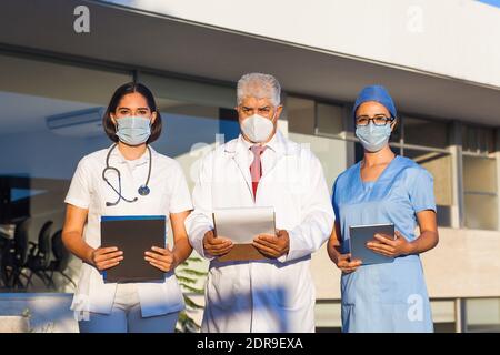 L'équipe latine de médecins regardent la caméra et Souriant en se tenant à l'extérieur de l'hôpital mexicain dans la ville de Mexico ou amérique latine Banque D'Images