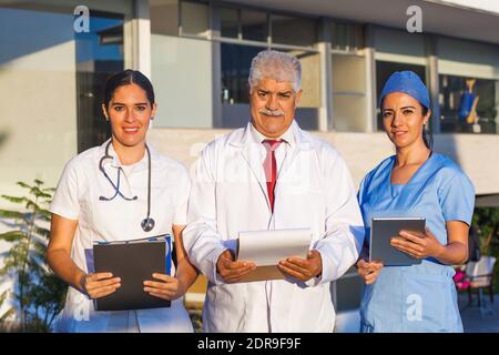 L'équipe latine de médecins regardent la caméra et Souriant en se tenant à l'extérieur de l'hôpital mexicain dans la ville de Mexico ou amérique latine Banque D'Images