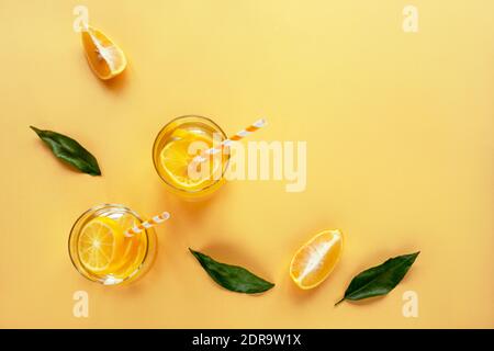 Morceaux de citron et feuilles vertes sur fond jaune avec deux verres de limonade. Vue de dessus, plat, espace de copie. Concept d'été. Banque D'Images